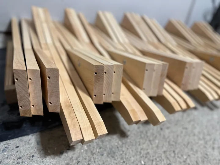 Several maple stand legs grouped together, showing the drilled ends and tapered profiles.