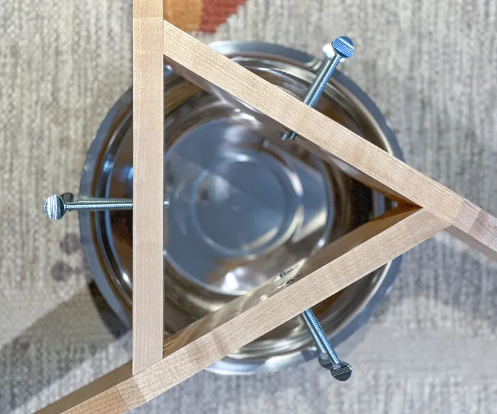 A maple stand surrounding a metal bowl, with thumb screws visible from above.