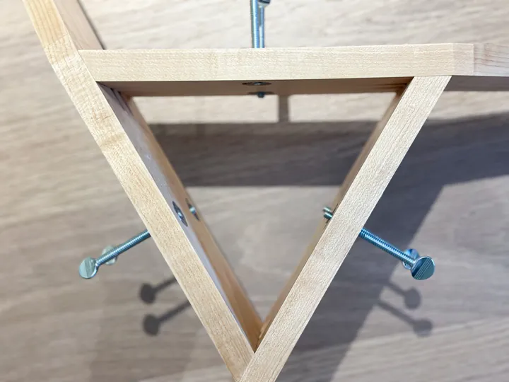 The triangular maple stand frame and thumb screws, viewed from above.