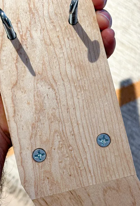 A close view of the maple joint with two wood screws and two protruding thumb screws.