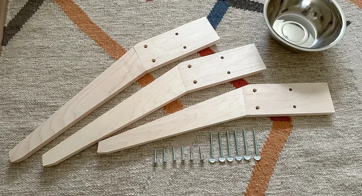 Three maple legs, wood screws, thumb screws, and a bowl laid out before assembly.