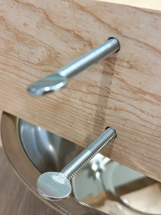 Two metal thumb screws passing through a maple stand leg above the bowl.