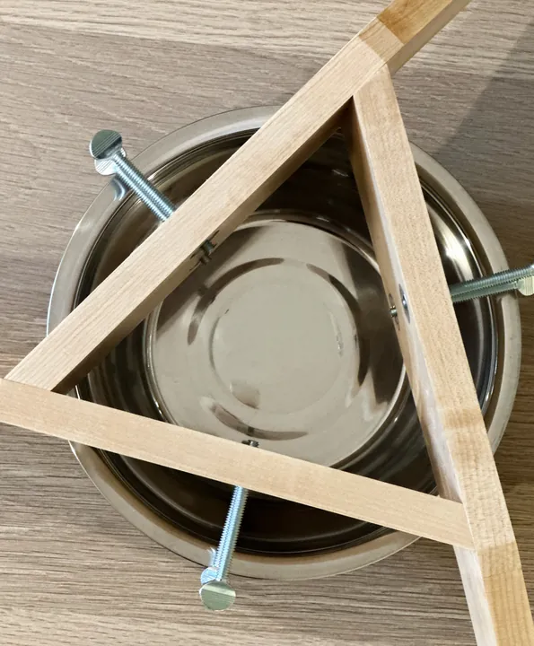 The triangular maple frame around a stainless steel bowl, viewed from above.
